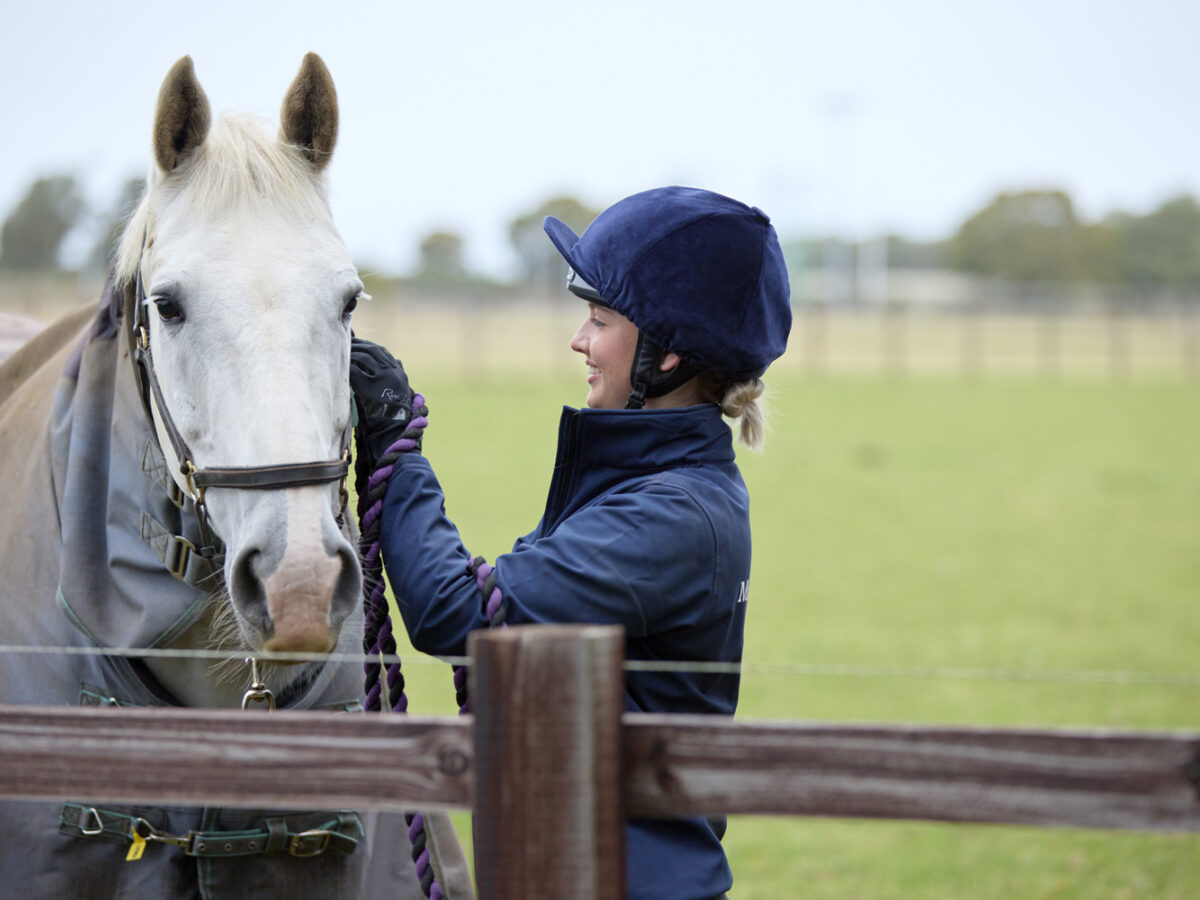 Student and white horse looking over fence