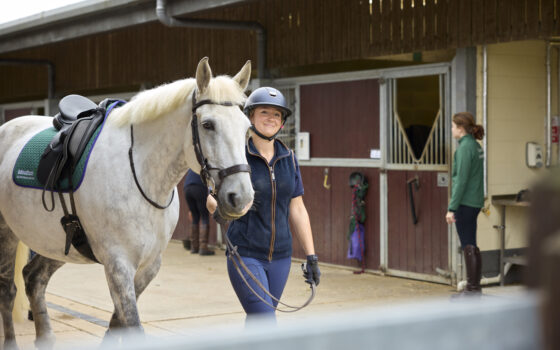 Student walking horse through the yard