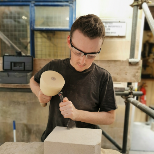 John chiseling block of stone