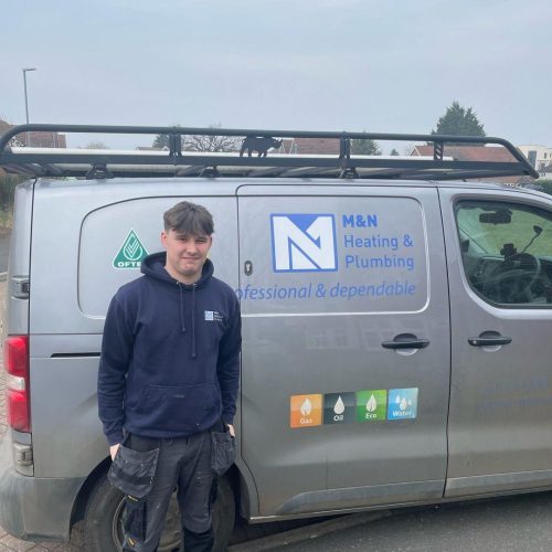 apprentice standing in front of a M&N plumbing and heating van that's grey